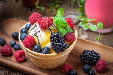 Tasty ice cream dessert with fruit in a waffle bowl.