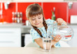 © Africa Studio - Adorable little girl pouring water in kitchen