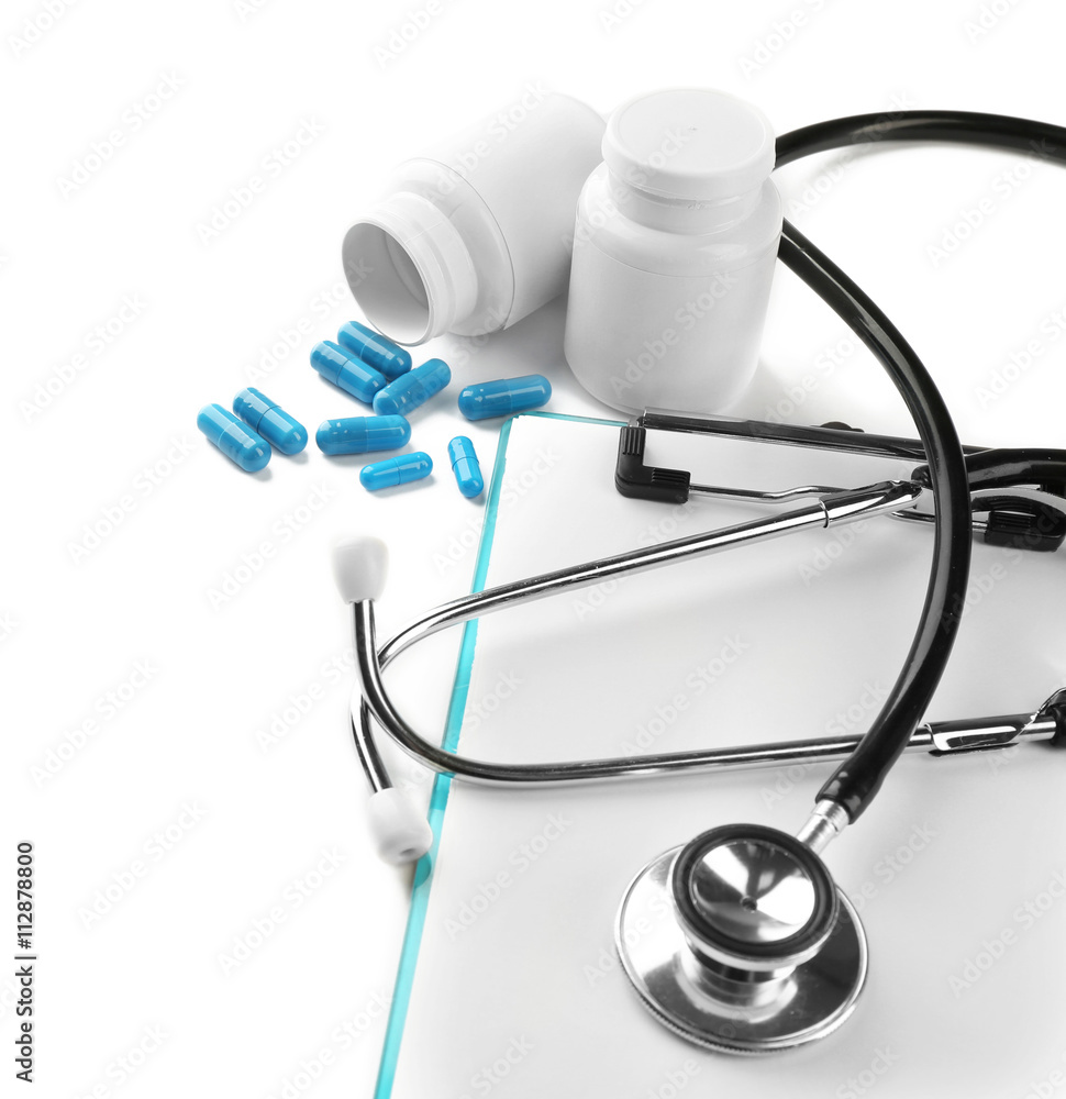 Medical concept. Clipping board with pills and a stethoscope on white background