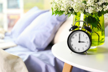 Alarm Clock And Flower Bouquet On A Side Table By The Bed