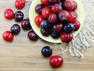 Sticker - red plum on wooden background top view