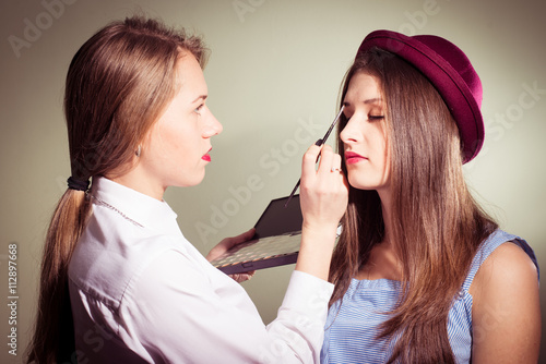 Girl doing another girl makeup - Buy this stock photo and explore 