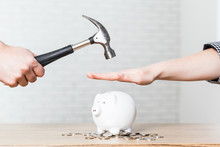 A Hand Holding A Hammer Which Is Raised Above A White Piggy Bank