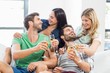 © WavebreakmediaMicro - Smiling friends sitting on sofa drinking alcohol