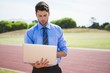 © WavebreakMediaMicro - Businessman using a laptop on the running track