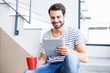 © WavebreakmediaMicro - Happy man on steps holding coffee cup and using digital tablet