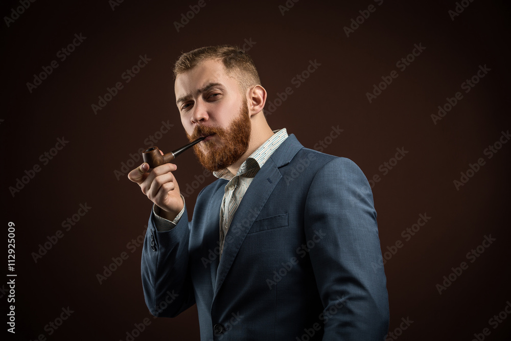 Portrait of handsome confident man in suit holding smoking pipe against of  brown background.Isolated. Stock Photo