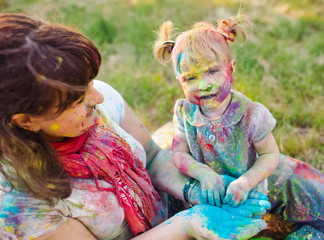 Family playing in the park. Family painted in the colors of Holi