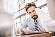 © Connect Images - Bearded businessman looking down at paperwork