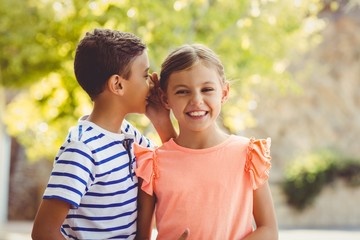 Wall Mural - Happy boy whispering a secret in girls ear