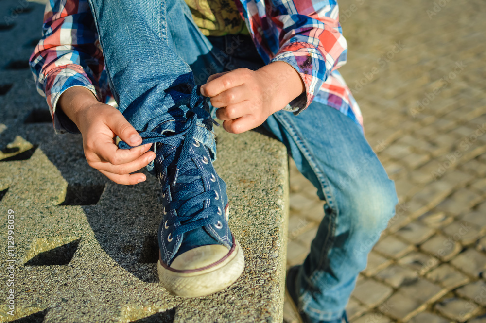 Closeup on kid hands tying laces ready for sport, school fun. Outside ...