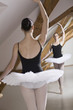 © fStop - A ballet dancer on pointe with one arm raised in front of a mirror in a ballet studio