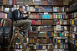 © fStop - A man sitting on a ladder in a bookstore reading a book