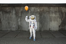 An Astronaut On A City Sidewalk Holding A Balloon