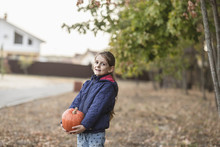 Portrait Of Cute Girl Holding Pumpkin Outdoors