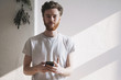 © fStop - Portrait of confident young man holding mobile phone at home