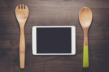 two wooden spoons and tablet computer on the brown table