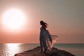 Silhouette of a girl standing on piers at the sunset