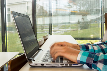 Student typing on laptop in empty seminar room