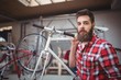 © Wavebreak Media - Portrait of mechanic carrying a bicycle in workshop