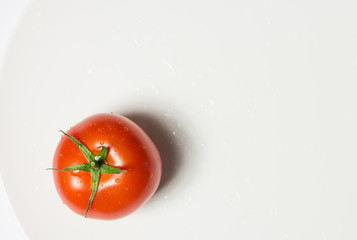 Washed ripe tomato on plate on white background, horizontal image