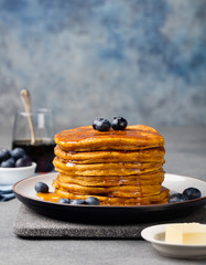 Wall Mural - Pumpkin pancakes with maple syrup and blueberries on a plate. Grey stone background