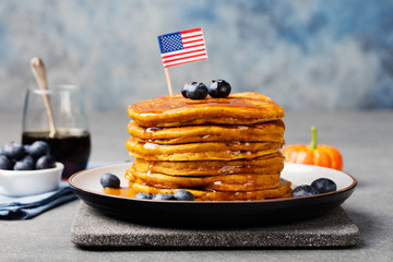 Wall Mural - Pumpkin pancakes with maple syrup and blueberries on a plate with American flag on top
