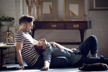 Homosexual Couple Relaxing On Floor In Living Room