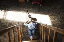 Young Man Lying By Stairs And Playing With Cat