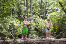 Two Boys (6-7, 10-11) Fishing From Fallen Tree