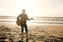 Man Playing Guitar On Beach At Sunset