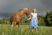 Cowgirl And Horse Standing In Grazing Field