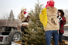Three Women Decorating Christmas Tree Outside