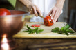 © Cavan Images - Midsection of woman cutting tomato slices by mint leaves on cutting board