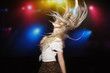 © Cavan Images - Woman with tousled hair dancing against disco light at party