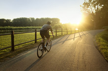 Young Man Riding Bicycle At Sunset
