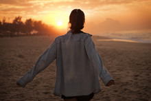 Young Woman Looking At Sunset On Beach