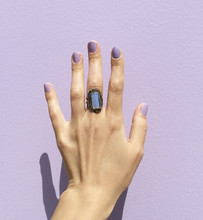 Woman's Hand With Ring Against Purple Wall