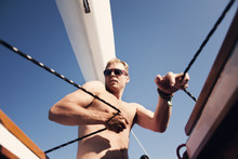 Young Man Pulling Ropes On Yacht