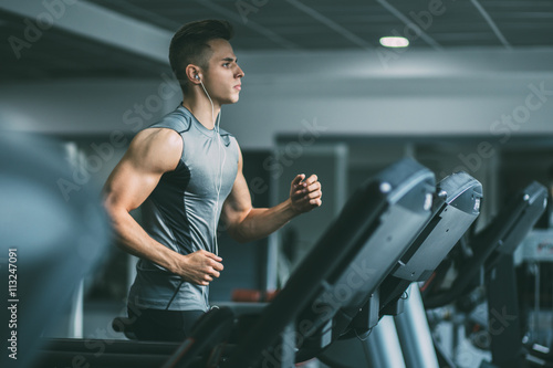 Young man in sportswear running on treadmill at gym Lerretsbilde