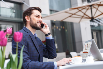 Wall Mural - Cheerful young man has discussing by telephone