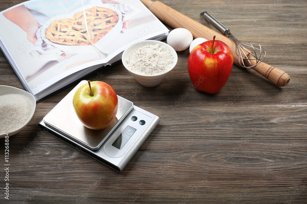 Apple with digital kitchen scales on wooden table. Cooking apple cake concept