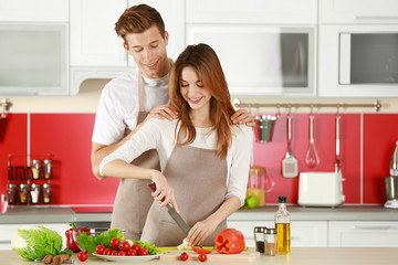 Wall Mural - Couple in aprons cooking in kitchen