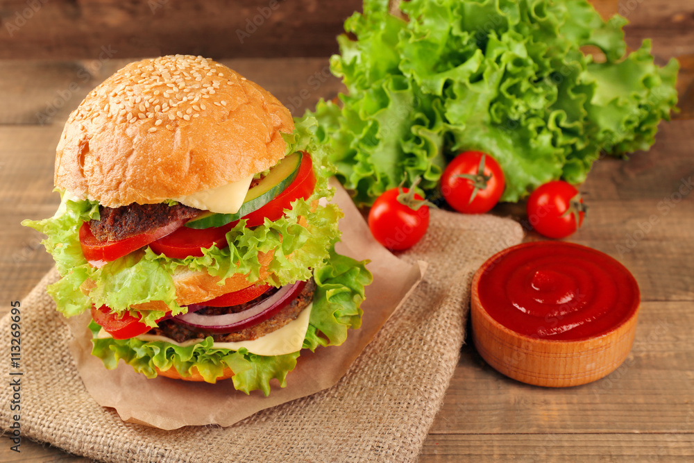 Big hamburger with ketchup on wooden background