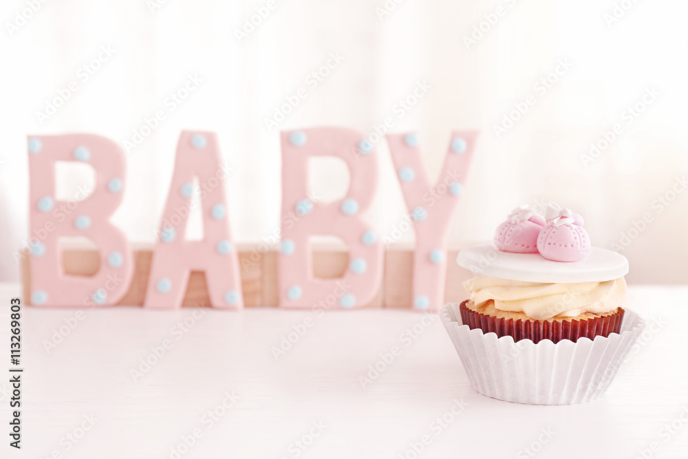 Word "Baby" with cupcake on light background
