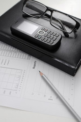 Canvas Print - The document of the report on work with a black notebook and glasses on a table of the manager