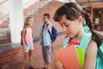 brunette girl mocked by two children behind her