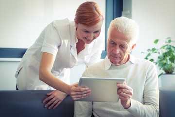 nurse showing report to senior man on tablet