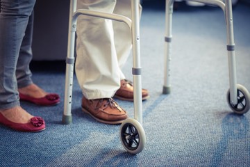 Senior woman helping senior man to walk with walker