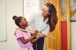 © WavebreakMediaMicro - Teacher assisting a girl to play a flute in classroom